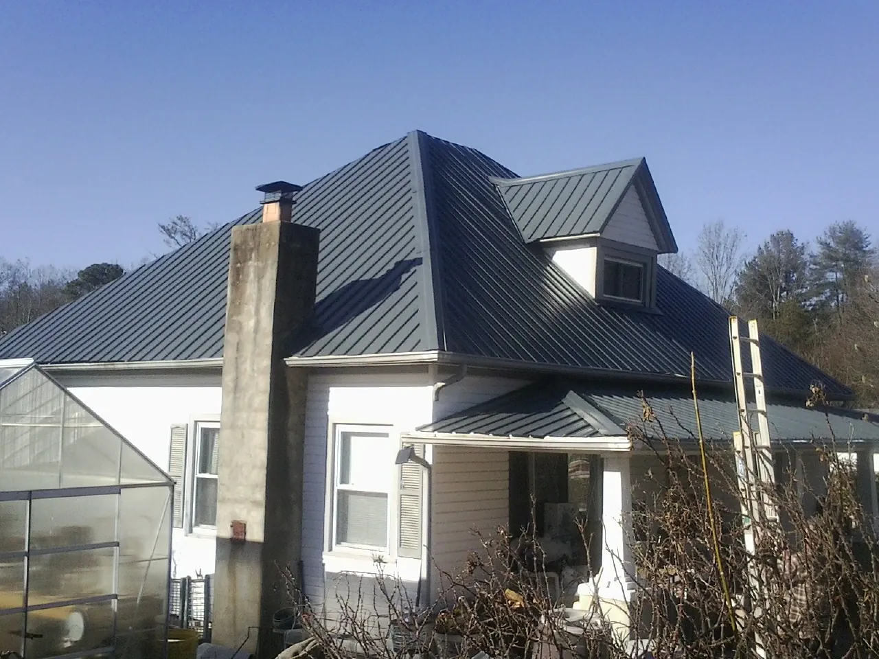 Dark blue standing seam metal roof on a white farmhouse with dormer — Slate & Tile Roof Repair by Roofing Brothers in Windham