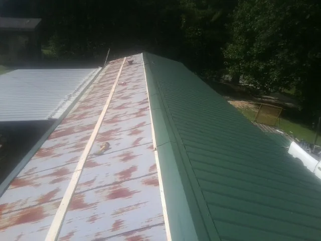Old rusted panels beside newly installed green metal roofing — Wind Damage Roof Repair by Roofing Brothers in Windham